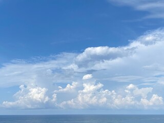 Wall Mural - Sky clouds over sea water.  Heaven clouds background. Divine blue skies, white clouds, sun rays. Beautiful cloudscape at sunny day. Spectacular cloudy sky on horizon over calm ocean.