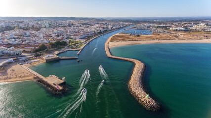 Canvas Print - Aerial view from the sky of the Portuguese coastline of the Algarve zone of Lagos city. Boats and ships are moving in the direction of the port.