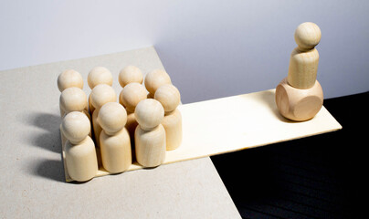 Wooden toys with figurines concept. Two figurines representing people of different skin colour, standing on a scale