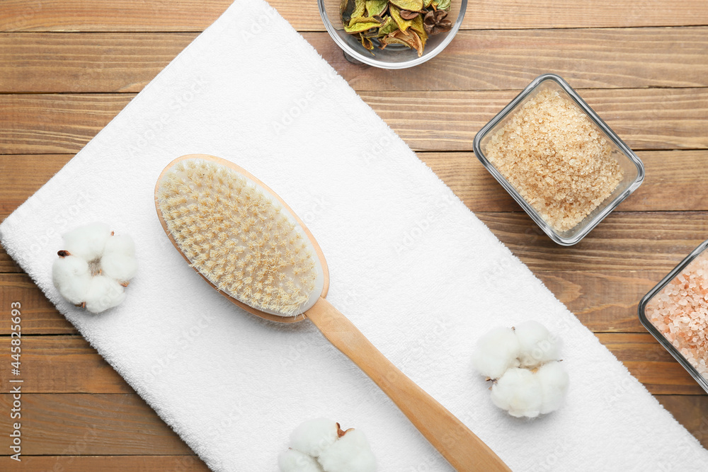 Massage brush and sea salt on wooden background