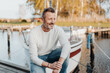 © contrastwerkstatt - Active sporty man crouching in front of his yacht at the marina
