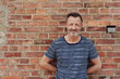 © contrastwerkstatt - Attractive bearded casual middle-aged man posing on a brick wall