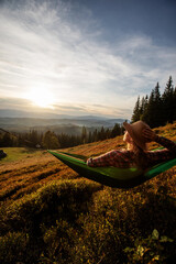 Canvas Print - Woman hiker resting after climbing in a hammock at sunset