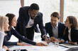 © fizkes - Focused African American business leader and employees discussing project on meeting, using scrum method with sticky notes for analyzing documents, marketing reports. Mentor, coach training interns