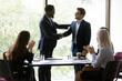 © fizkes - Happy African American business leader shaking hands with promoted employee. Boss hiring new team member, welcoming worker, expressing recognition for good work. Audience team clapping hands
