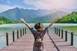 © Goffkein - Traveler girl backpacker with open raised arms standing alone on pier and staring at lake and mountains. Enjoying free moment life and serene quiet peaceful atmosphere in nature. Back view