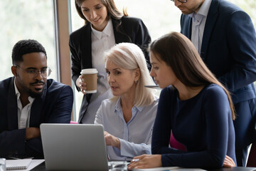 Poster - Mature corporate coach, mentor, teacher training diverse intern team at laptop, explaining learning webinar, showing online virtual video presentation, teaching new employees