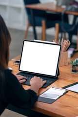 Rear view of woman working on tablet with keyboard while sitting at office desk.