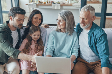 Sticker - Modern family spending time together and smiling while sitting on the sofa at home