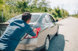 © Charnchai saeheng - Man pushing a broken car breakdown on the road hot day. Car broken concept.