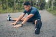© Charnchai saeheng - young man stretching in the park before running. Young man workout before fitness training at the park. Healthy and exercise young man warming up on the road in the forest.