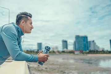 Wall Mural - sport man standing after running and holding water bottle drink. Sport thirsty and resting after exercise.