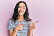 © Krakenimages.com - Hispanic teenager girl with dental braces wearing casual clothes smiling and looking at the camera pointing with two hands and fingers to the side.