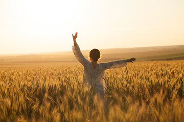 Girl in a dress in the middle of a field of ripe rye