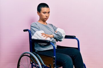 Wall Mural - Beautiful hispanic woman with short hair sitting on wheelchair skeptic and nervous, disapproving expression on face with crossed arms. negative person.