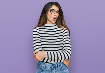 Sticker - Young beautiful teen girl wearing casual clothes and glasses afraid and shocked with surprise expression, fear and excited face.