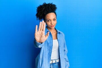 Sticker - Young african american girl wearing casual clothes doing stop sing with palm of the hand. warning expression with negative and serious gesture on the face.