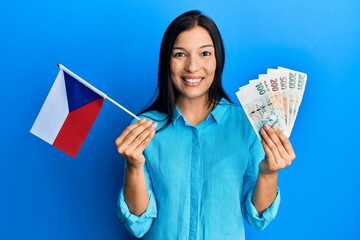 Sticker - Young latin woman holding czech republic flag and koruna banknotes smiling with a happy and cool smile on face. showing teeth.