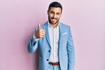 Young hispanic businessman wearing business jacket doing happy thumbs up gesture with hand. approving expression looking at the camera showing success.