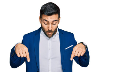 Sticker - Young hispanic man wearing business jacket pointing down with fingers showing advertisement, surprised face and open mouth