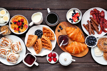 Breakfast or brunch table scene. Overhead view on a dark wood background. Selection of sweet and savory food items.