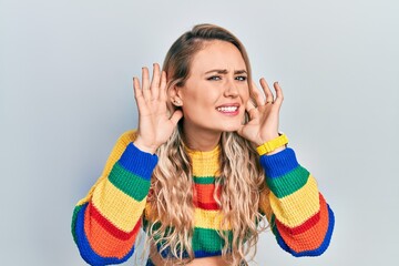 Sticker - Beautiful young blonde woman wearing colored sweater trying to hear both hands on ear gesture, curious for gossip. hearing problem, deaf