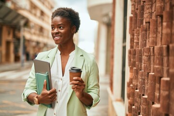 Sticker - Young african american businesswoman holding laptop drinking coffee at the city