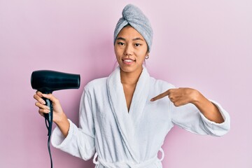 Sticker - Young chinese woman wearing shower towel cap and bathrobe holding dryer pointing finger to one self smiling happy and proud