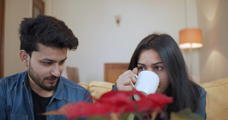 Wall Mural - Young Indian couple drinking coffee and spending time at home