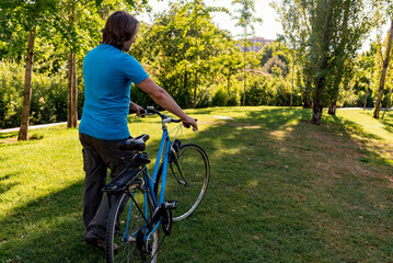 Wall Mural - Unrecognizable man walking in the park with his bicycle