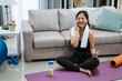 © PR Image Factory - sport technology and healthy lifestyle concept. smiling asian chinese woman in wireless earphones listening to music on smartphone at home living room. fitness young girl in bluetooth headphones.