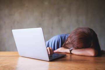 Canvas Print - A businesswoman or a student get tired and asleep at desk while working on laptop computer at home