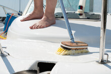 Man Washing White Boat With Brush And Pressure Water System At Pier.