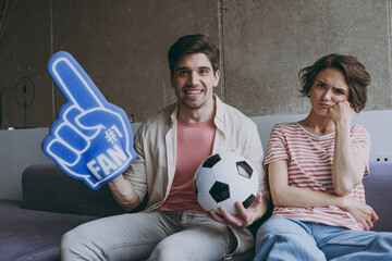 Wall Mural - Excited couple sad woman man friend football fans in casual clothes foam glove finger up support favorite team with soccer ball shout indoors at home flat watch tv People sport leisure family concept