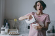 Young excited surprise brunette housewife woman in casual clothes striped t-shirt using mixer whips yolks beats eggs cooking food in light kitchen at home alone. Healthy diet bakery lifestyle concept