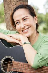 Poster - Portrait of smiling pretty senior woman leaning on acoustic guitar and pondering over something