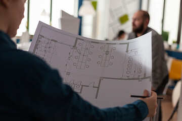 Architects looking at plans of blueprints for design of building model sketch layout maquette. Professional adult team working on architectural construction drawing as job occupation