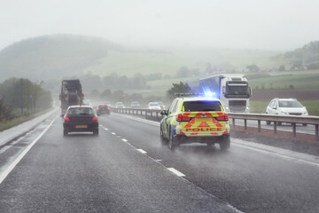 Wall Mural - Police siren flashing blue lights on motorway in bad weather conditions