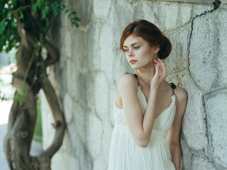 pretty woman in white dress posing in nature near a tree Greece