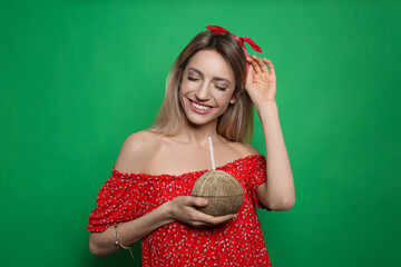 Wall Mural - Young woman with fresh coconut on green background. Exotic fruit