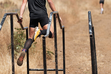 Participant in extreme obstacle race climbing over hurdle