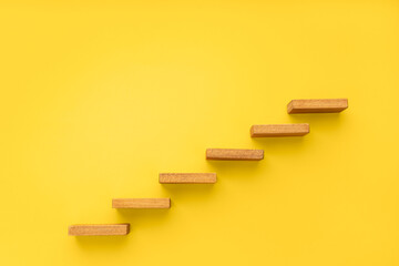 Wall Mural - Wooden staircase on yellow background. Growth, increasing business, success process concept. Copy space