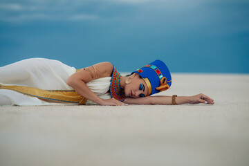 Wall Mural - Woman in image of egyptian queen Nefertiti lies on sandy in desert.