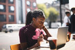 © Rawpixel.com - Woman with braids using a laptop at an outdoor cafe