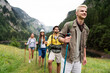 © NDABCREATIVITY - Group of happy friends with backpacks hiking together