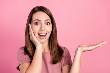 Poster - Photo of young girl amazed shocked hold hand product promo offer advertise isolated over pink color background