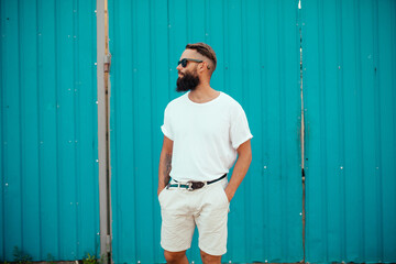 Street portrait of a young bearded hipster guy wearing a white blank t-shirt. Mock-up for print. T-shirt template.