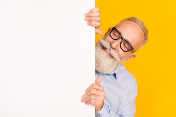 Sticker - Photo of cheerful positive happy old man look empty space blank board isolated on yellow color background