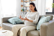 © Syda Productions - pregnancy, health and glycemia concept - pregnant asian woman checking blood sugar level with glucometer and lancing device at home
