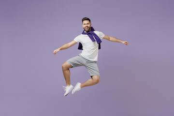 Wall Mural - Full size body length fun young brunet man 20 wear white t-shirt purple shirt jump do clapping gesture with legs isolated on pastel violet background studio portrait. People emotion lifestyle concept